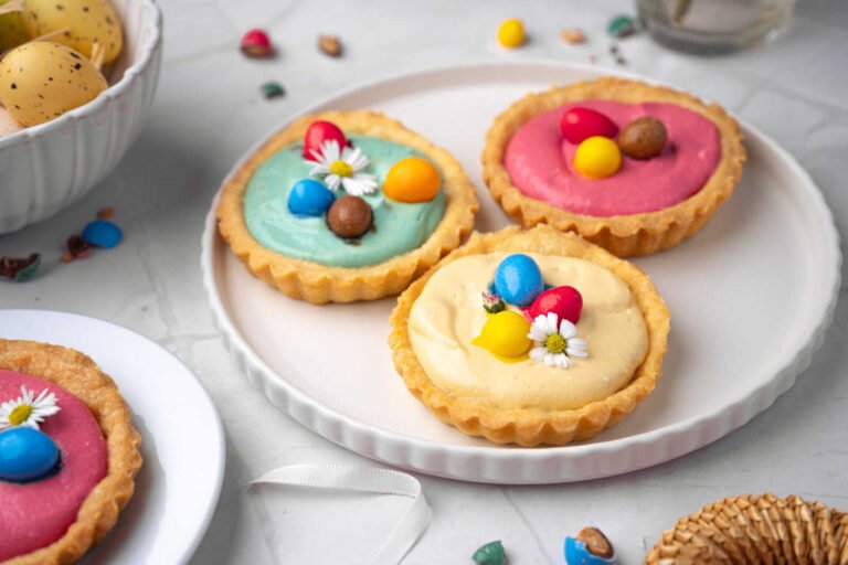 Colorful Easter mini cheesecake tart desserts with candy eggs.
