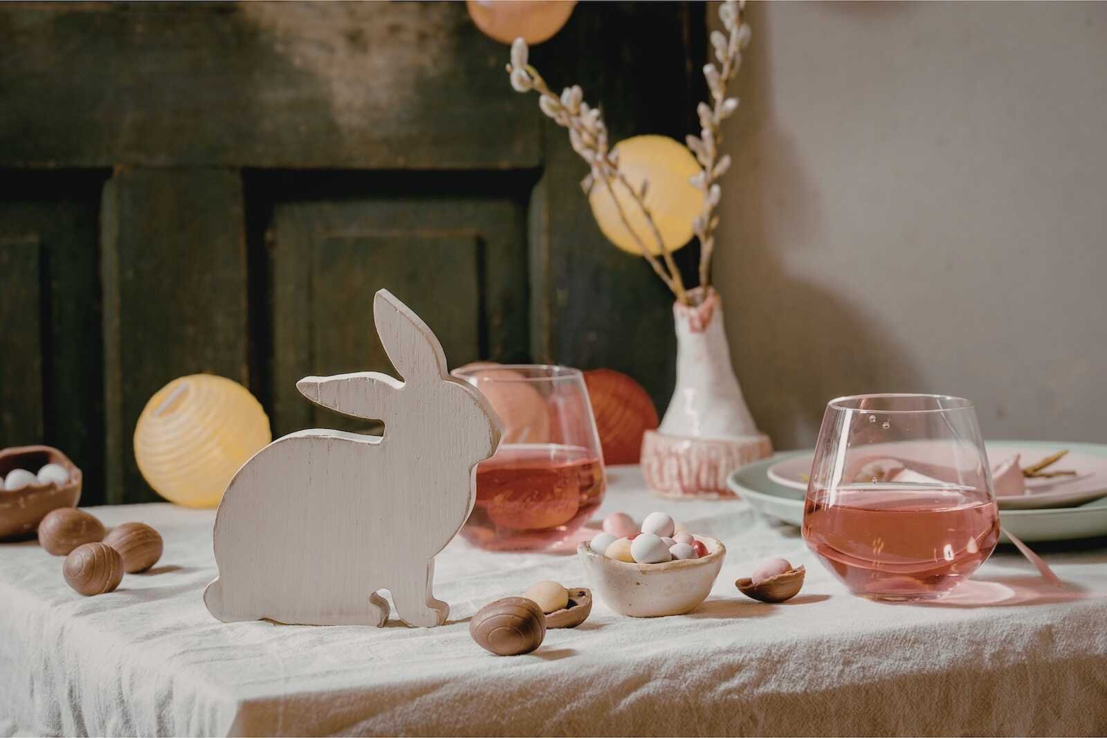 Easter table decor with wooden bunny, pastel candies, and spring decorations representing Easter traditions around the world.