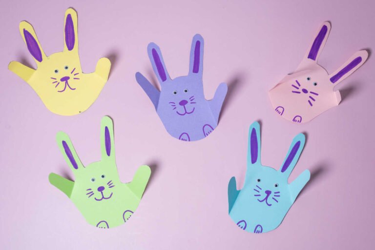 Bunny Handprint Craft finished colorful paper bunnies arranged on a pastel background with cute drawn faces.
