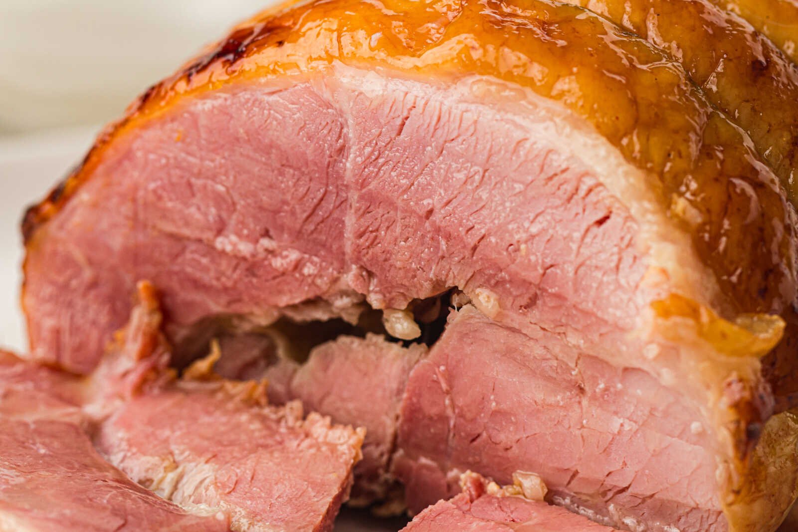 Close-up of sliced honey glazed ham showing tender pink meat and a glossy caramelized honey coating.